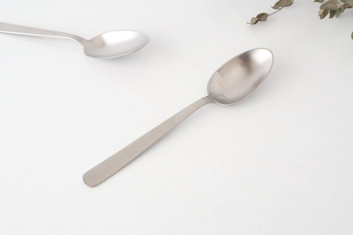 A metal dinner spoon shown on a white background with a second spoon partially visible.