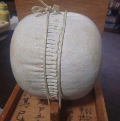 A white traditional kemari (soccer) ball displayed on a wooden stand.