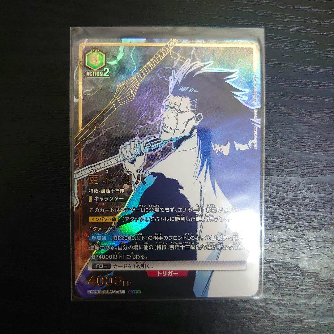 Photograph of the holographic trading card 更木剣八 (BLEACH) in a protective sleeve on a dark surface.