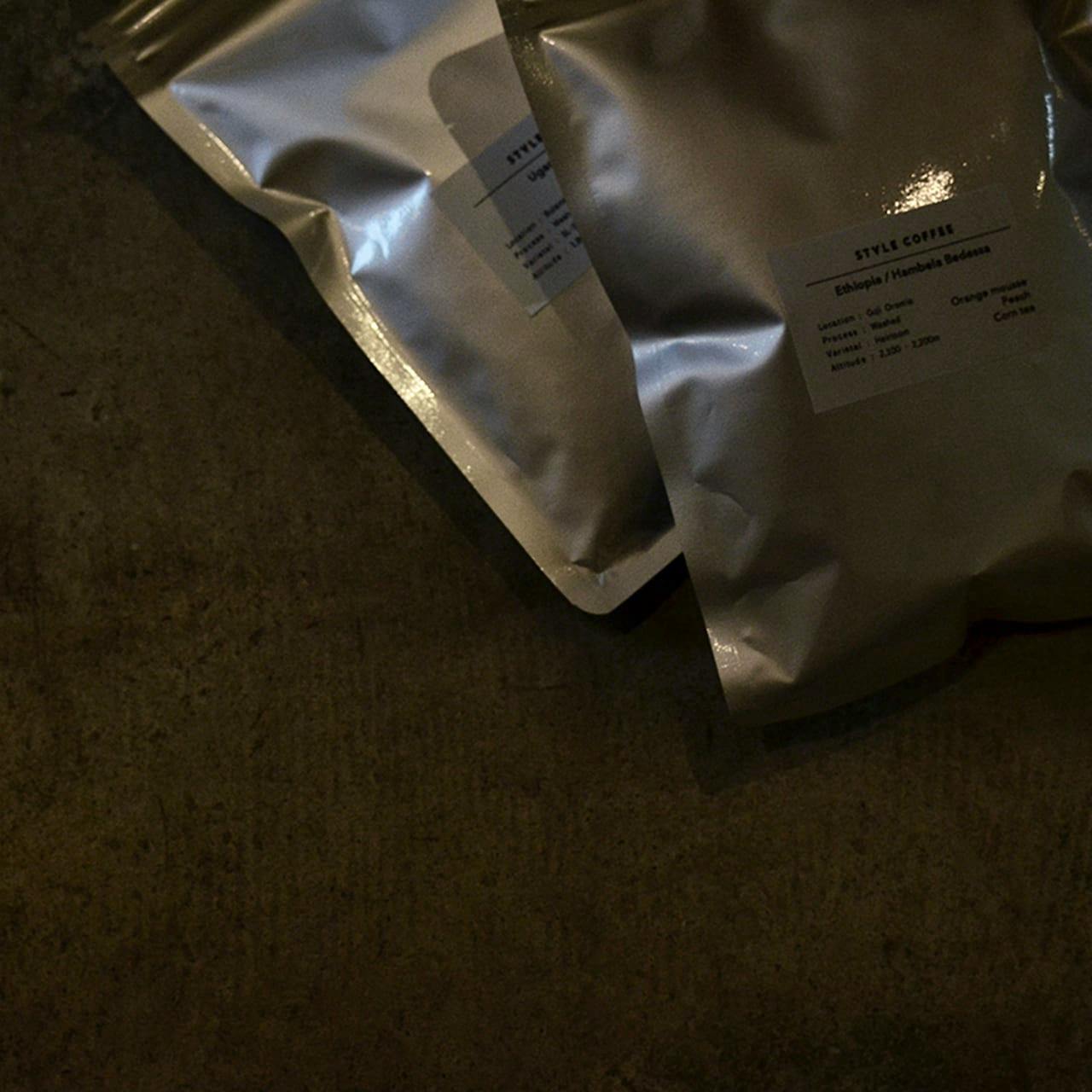 Two silver sealed coffee bags lying on a dark surface with small product labels visible.