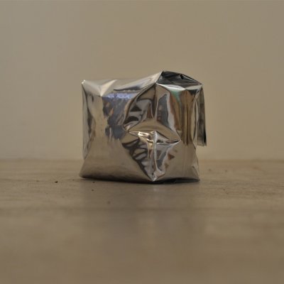 A crumpled silver foil bag placed on a neutral surface, representing the roasted coffee packaging.