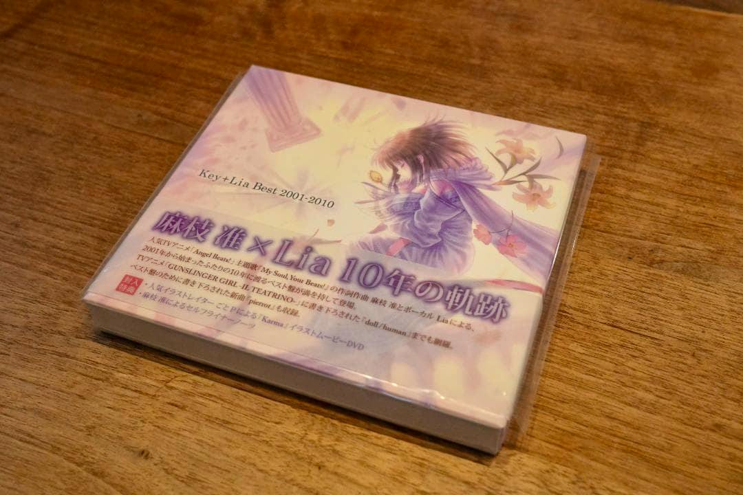 Sealed Key+Lia Best 2001-2010 DVD with CD case on a wooden table showing illustrated cover art.