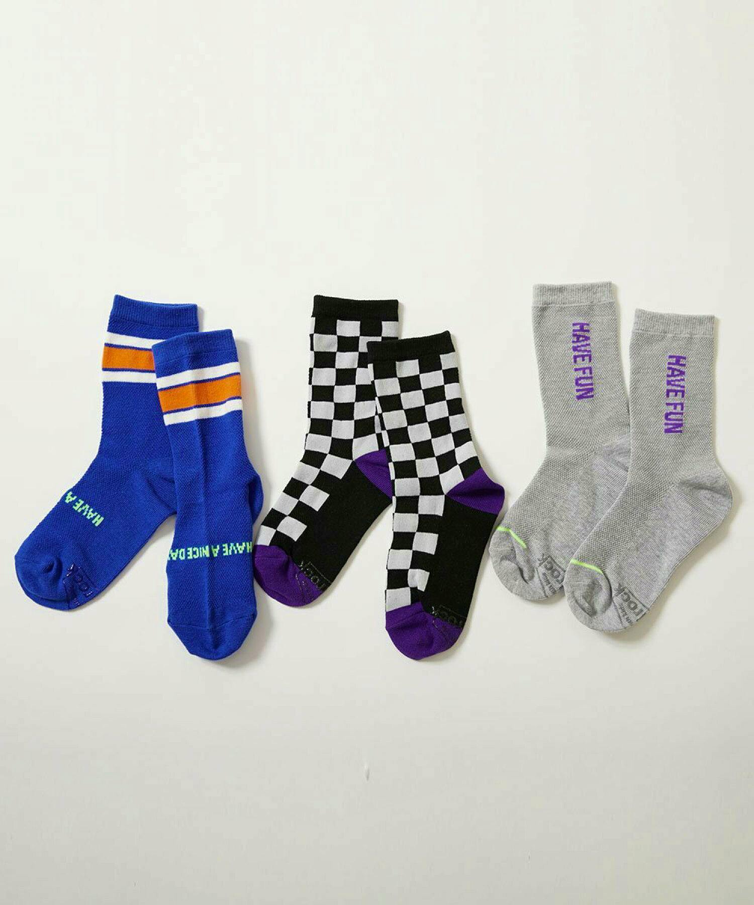 Three pairs of children's socks laid flat showing a blue striped pair, a black-and-white checkered pair with purple accents, and a gray pair with "HAVE FUN" text.