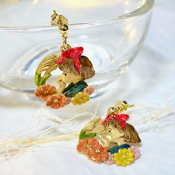 A pair of non-precious metal earrings depicting Kiki's profile from Kiki's Delivery Service with a red bow and colorful flowers, one hanging from a glass dish.
