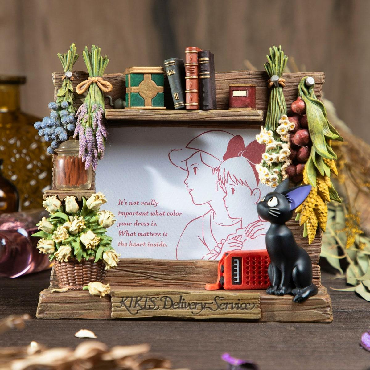 Front view of the Kiki's Delivery Service wooden photo frame showing decorative books, dried flowers, and the black cat Jiji.