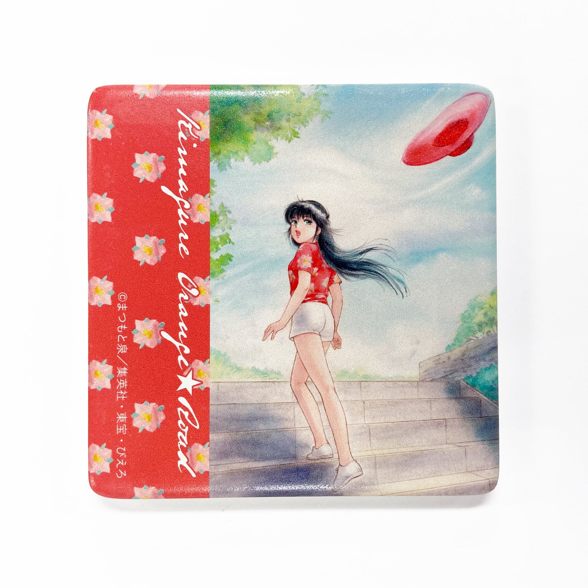 A ceramic coaster showing the illustrated front with a girl standing on steps, a red floral side band, and a sky background.