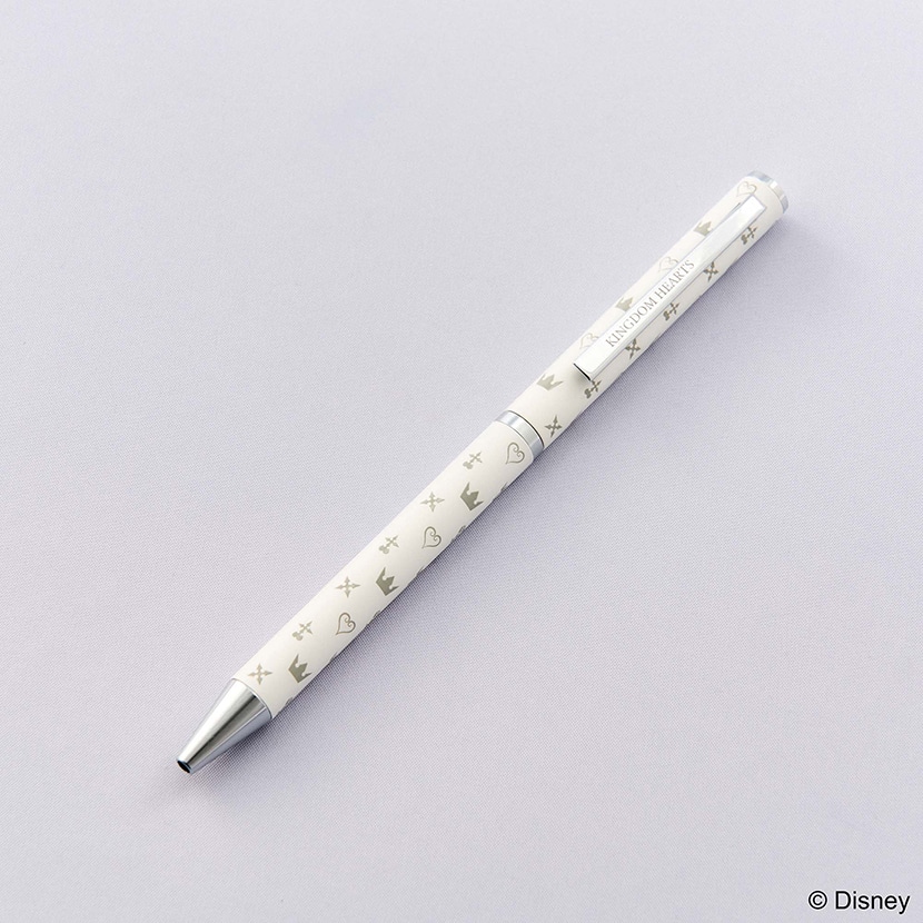 White Kingdom Hearts ballpoint pen with silver tip and small crown and heart motifs lying on a light background.