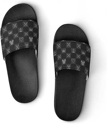 Top-down photo of a pair of black Kingdom Hearts slide slippers with checkerboard-patterned straps showing crowns, hearts, and Mickey head silhouettes.