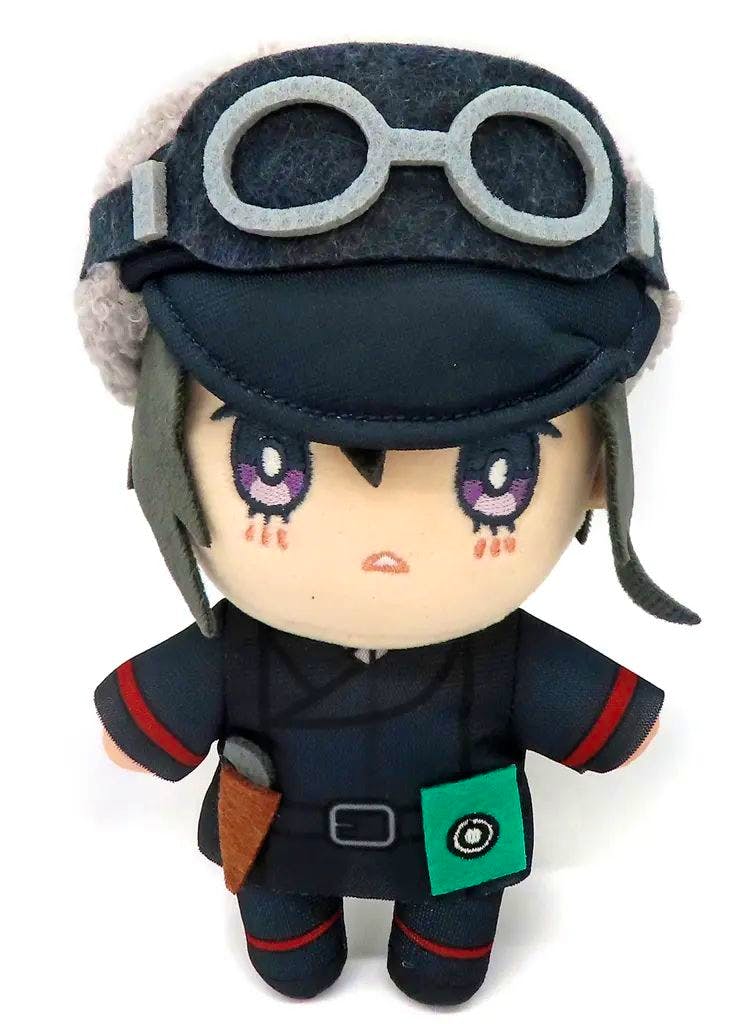 Front view of the Kino plush toy wearing a dark hat with goggles and a small green pouch.