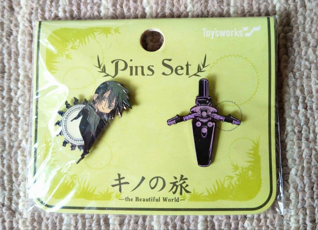 Two enamel pins from the Kino's Journey pin set (Kino and Hermes) attached to a yellow backing card.