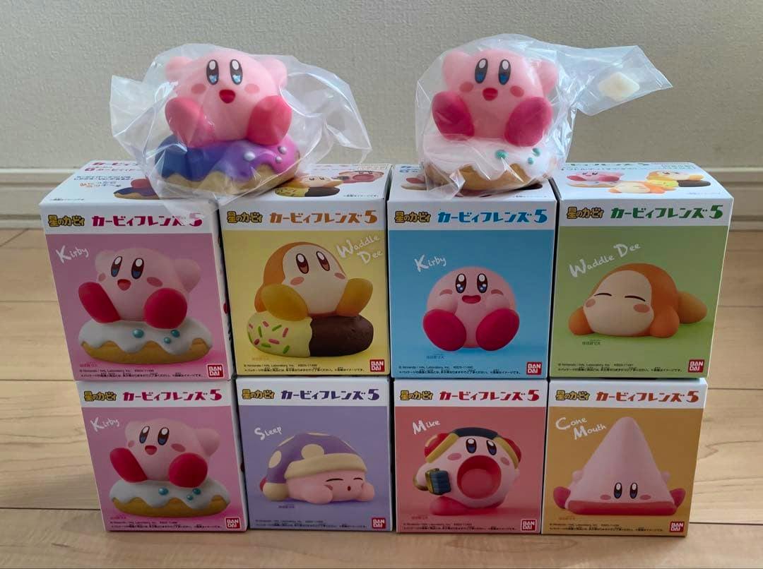 Full set of eight “Kirby Friends 5” boxed plastic figures arranged in two rows with two loose Kirby figures in plastic bags on top.