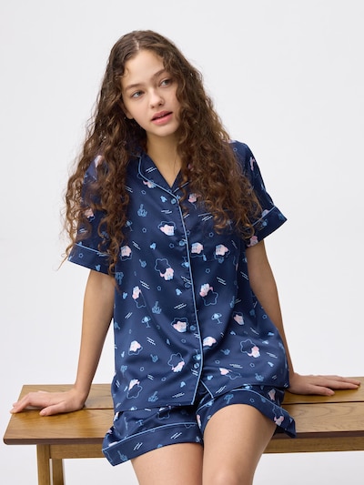 A model wearing navy satin short-sleeve pajama top and matching shorts with a Kirby print.