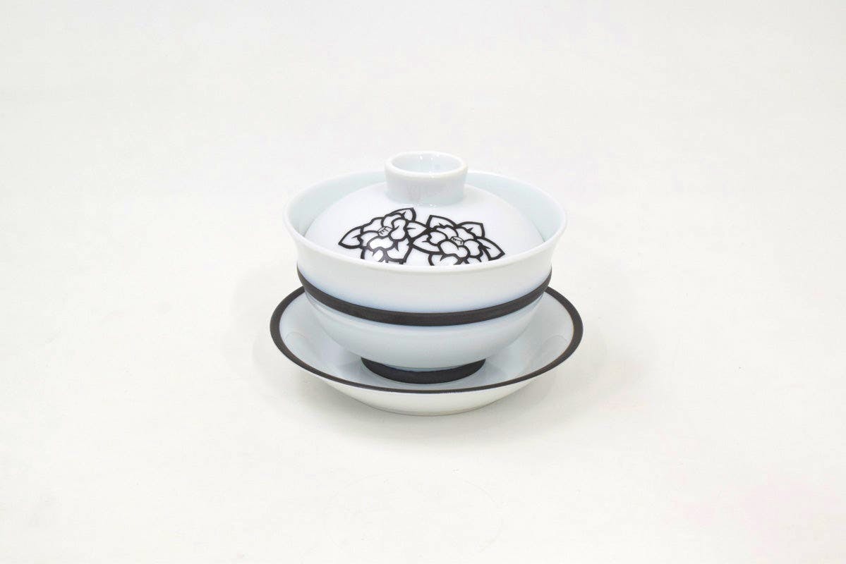 Porcelain lidded bowl (gaiwan) with matching saucer, white with a black rim and a black floral design on the lid.