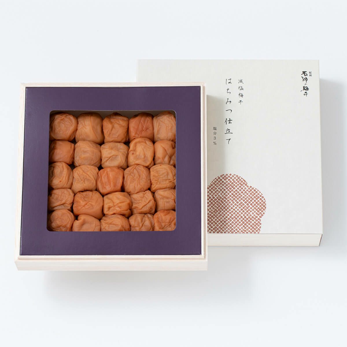 A boxed set of preserved plums arranged in a grid with the product's outer box beside it.
