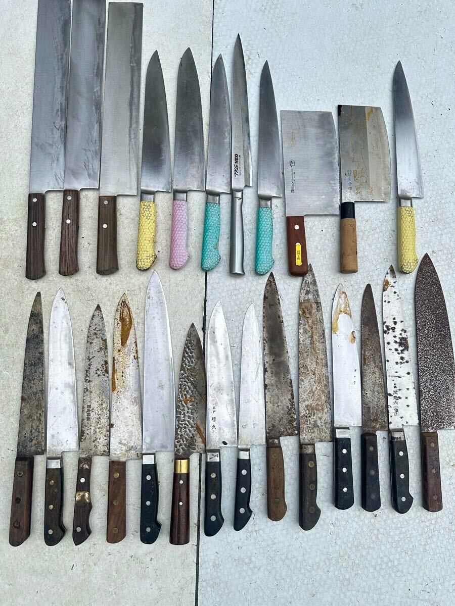 Top-down photo of multiple Japanese chef knives and cleavers arranged flat on a light surface.