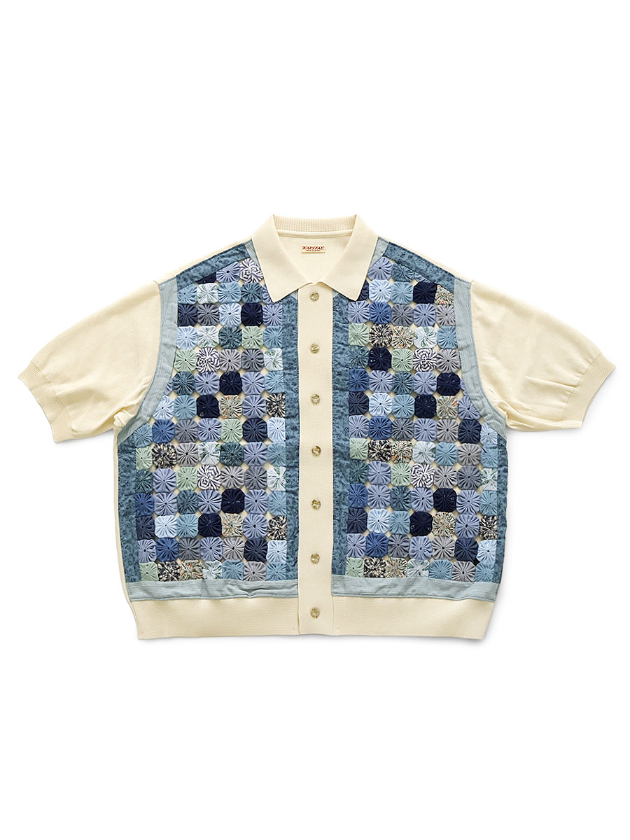 Cream short-sleeve polo shirt with a button front and blue-toned yo-yo quilt patchwork panels on the front.