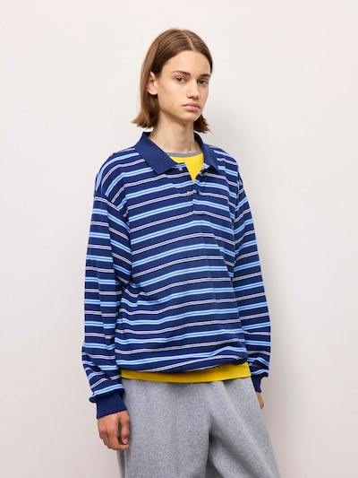 Model wearing a blue striped long-sleeve oversized polo shirt.