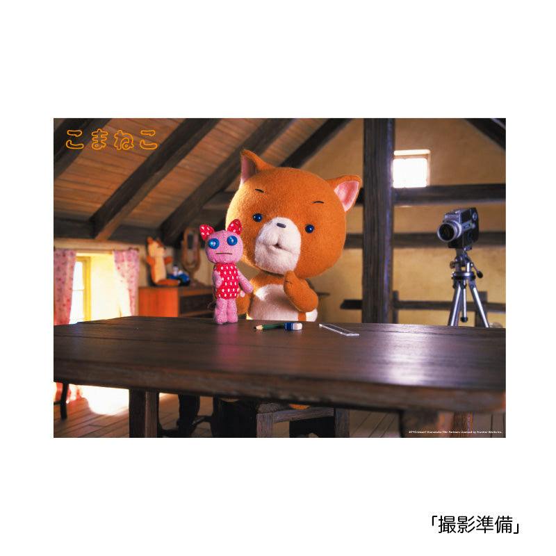 Poster showing an orange plush cat character holding a small pink doll on a wooden table in an attic setting with a camera on a tripod.