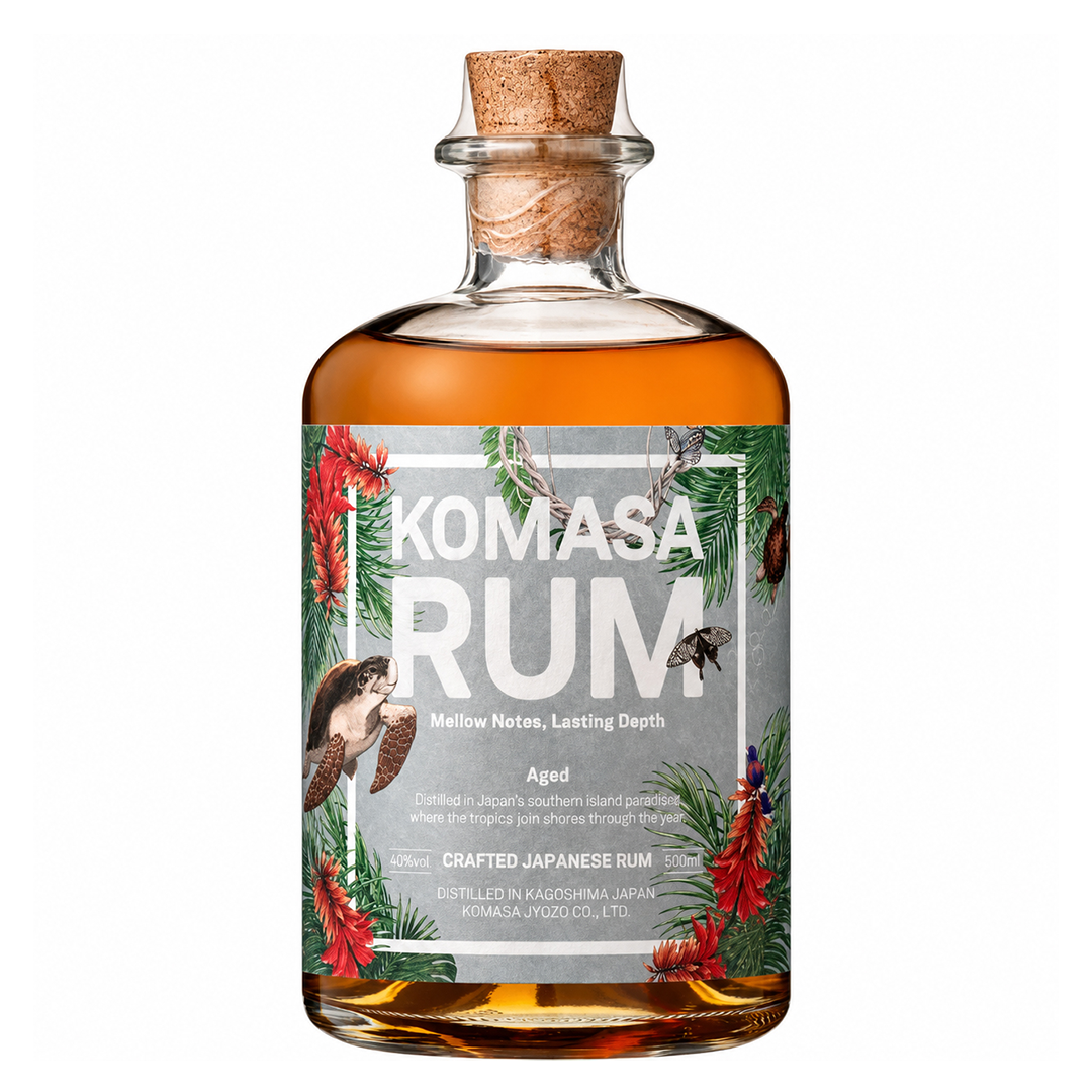 A glass bottle of KOMASA RUM with a cork stopper and a decorative tropical label.