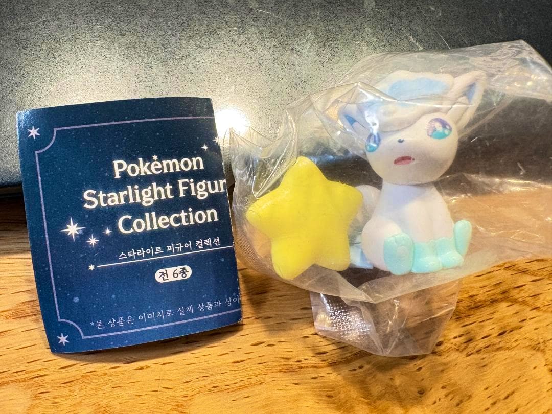 Alolan Vulpix plastic figure in its clear bag shown beside the Starlight Figure Collection leaflet.