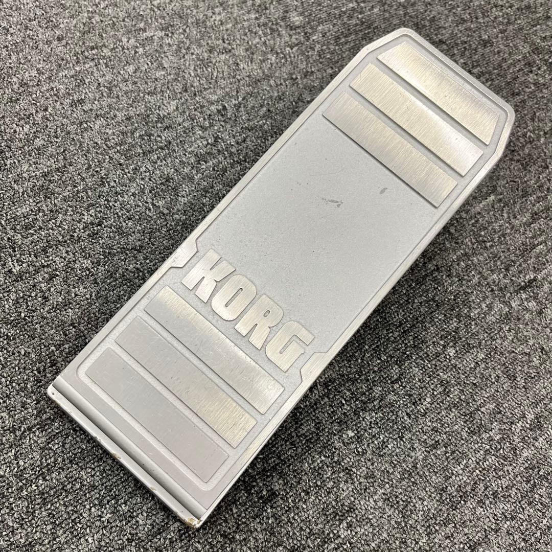 Top view of a silver KORG XVP-10 expression pedal with KORG logo, lying on a carpeted surface.