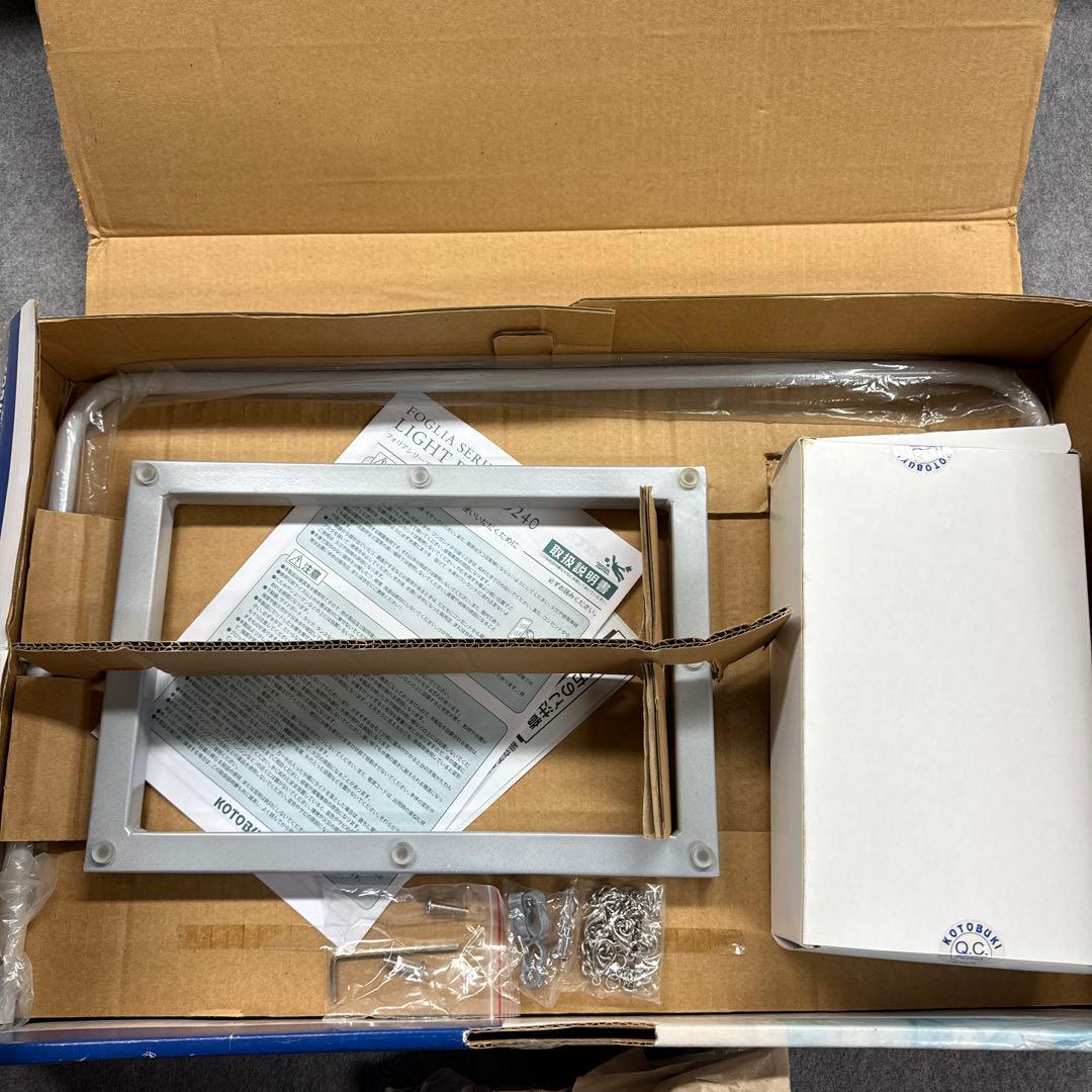 Opened box showing the aquarium lightboard parts and accessories, including a rectangular frame, chains, and a white component box.