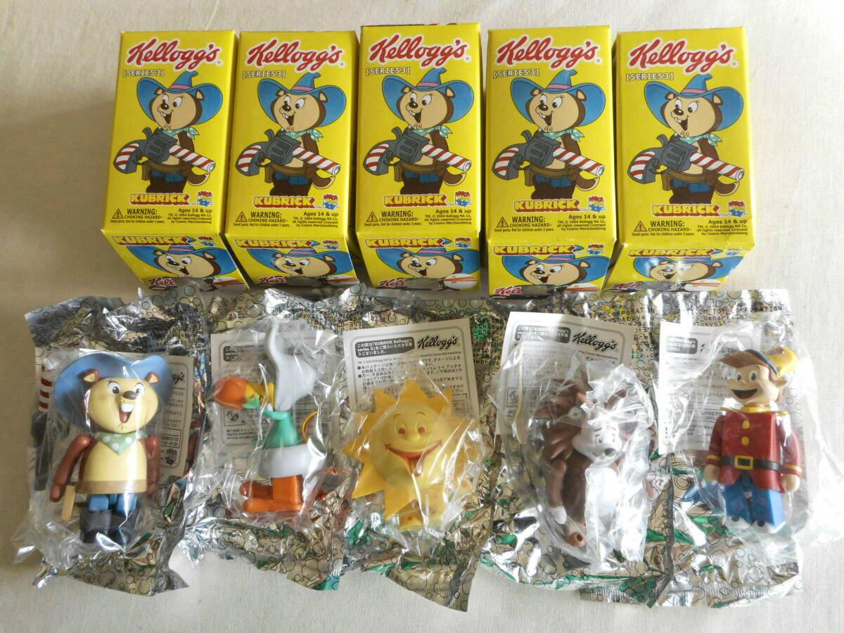 Five yellow Kellogg's KUBRICK Series 3 boxes with five sealed plastic figure toys displayed below them.