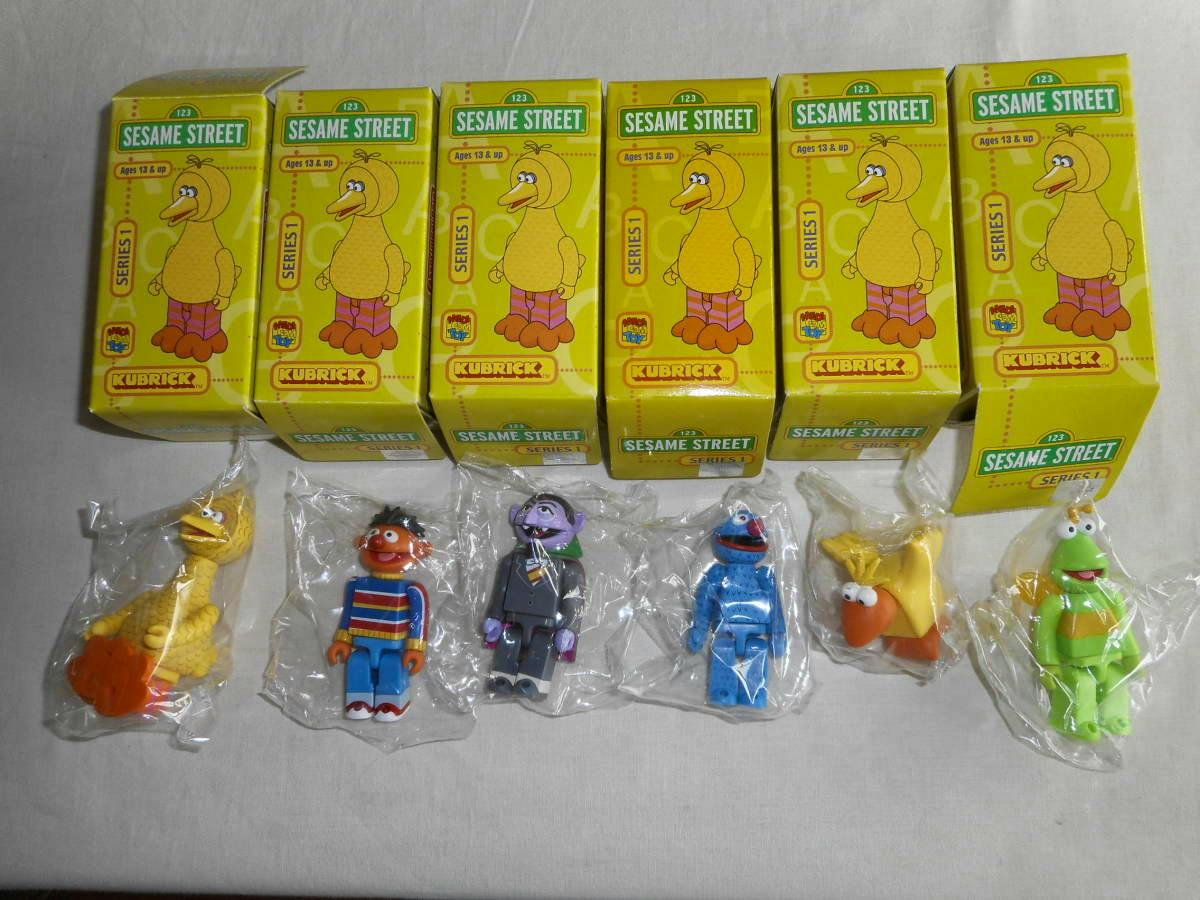 Six yellow Kubrick SESAME STREET Series 1 boxes with six small Sesame Street Kubrick plastic figures shown below in individual clear bags on a cloth surface.