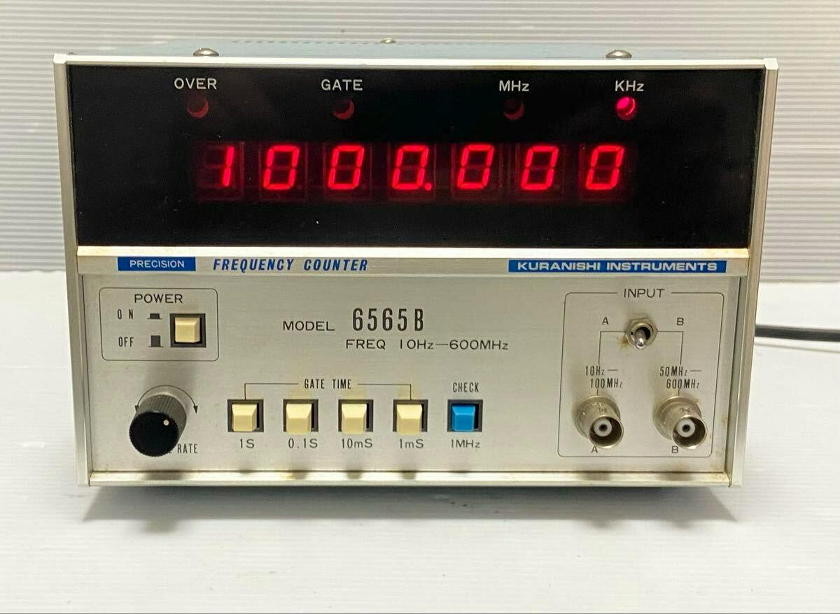 Front view of the KURANISHI MODEL 6565B frequency counter showing its LED display, front controls, and input connectors.