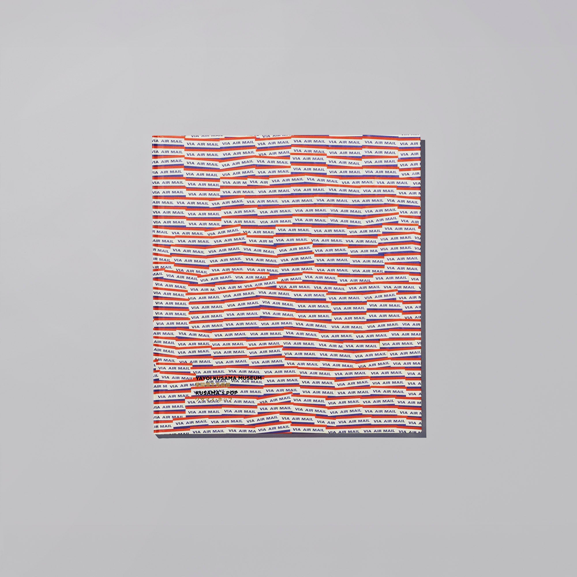 Closed Catalogue 017 'KUSAMA’s POP' photographed on a gray background, showing a cover with repeating red and blue horizontal text stripes.