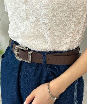 Brown synthetic leather belt with a decorative silver buckle worn at the waist over jeans and a lace top.