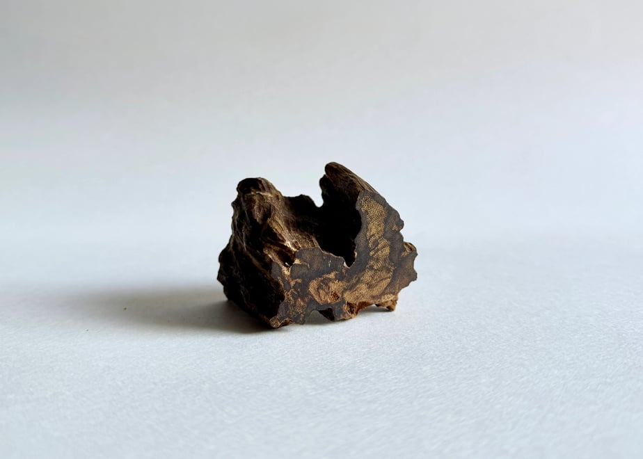 A small piece of agarwood incense (伽羅) placed on a white surface with soft lighting.