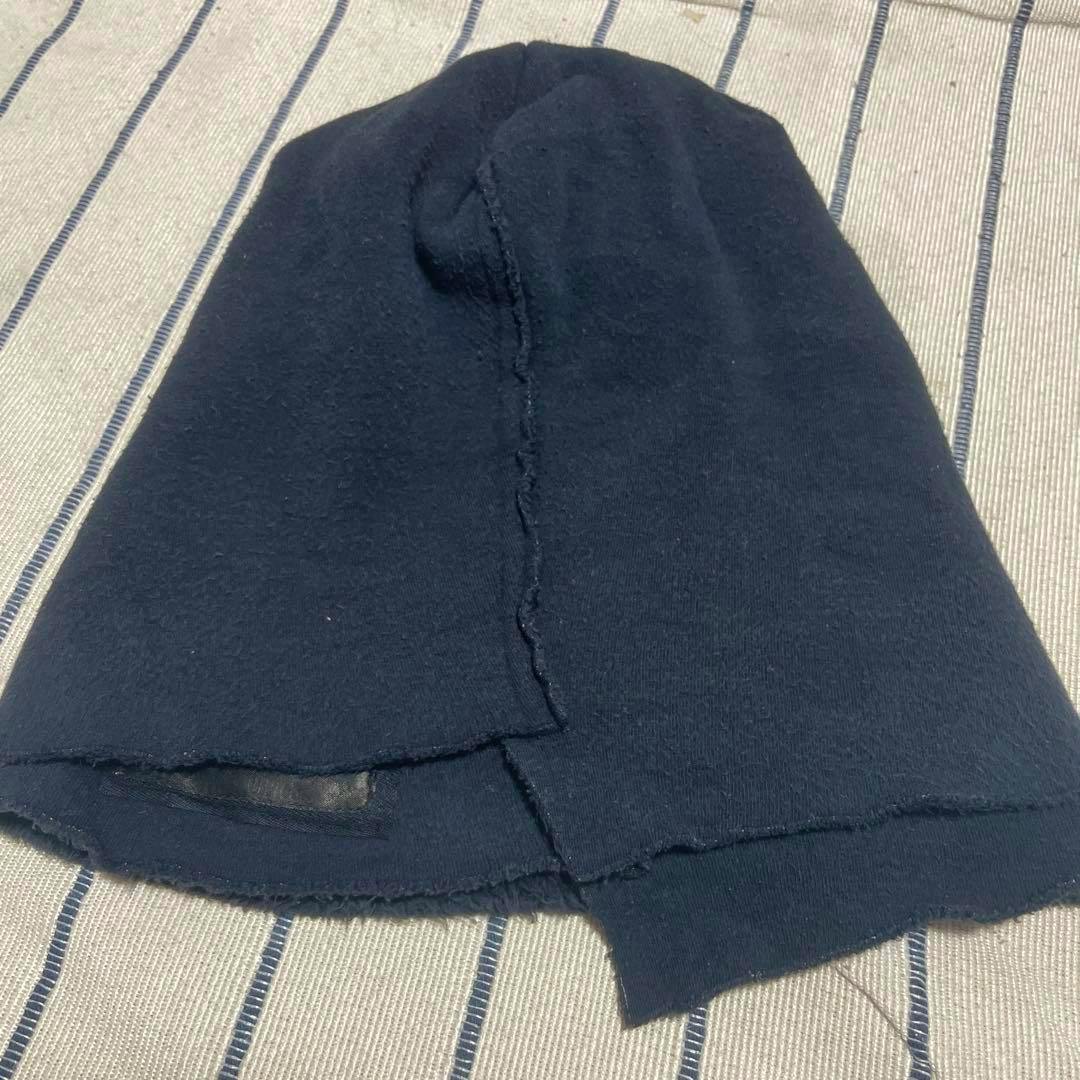 A dark navy L.G.B. knit beanie laid flat on a striped fabric background.