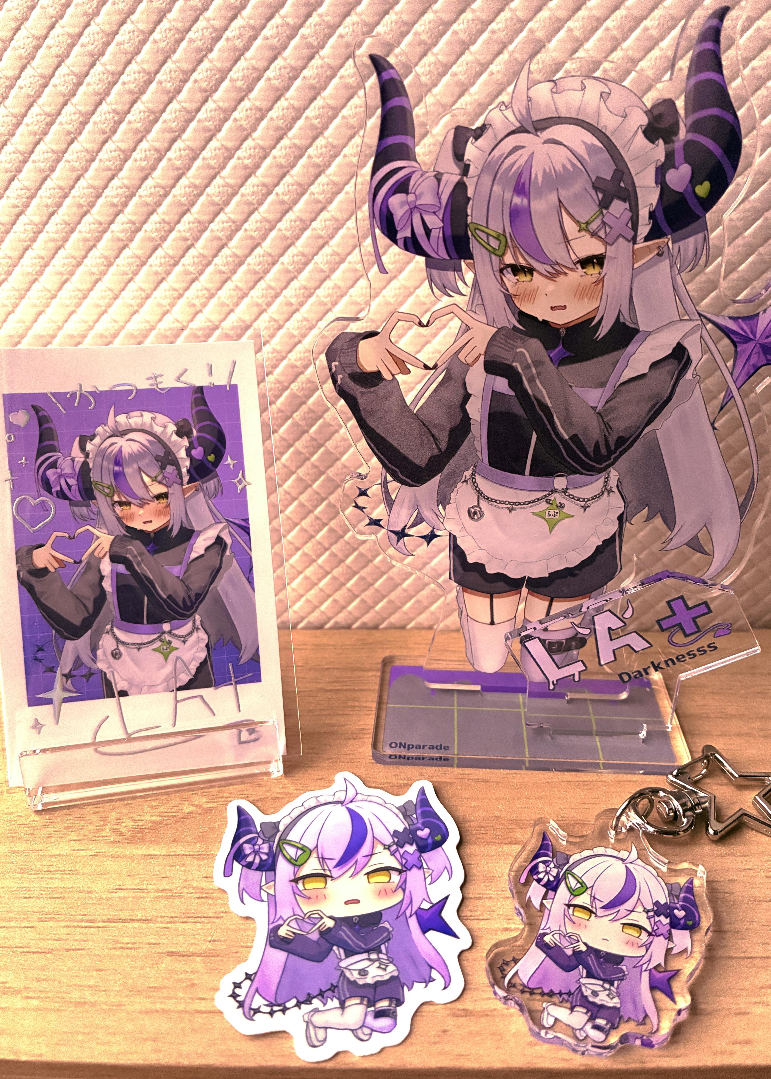 Photo of the acrylic decorative stand with matching stickers and an acrylic keychain from the Laplace Darkness set displayed on a wooden surface.