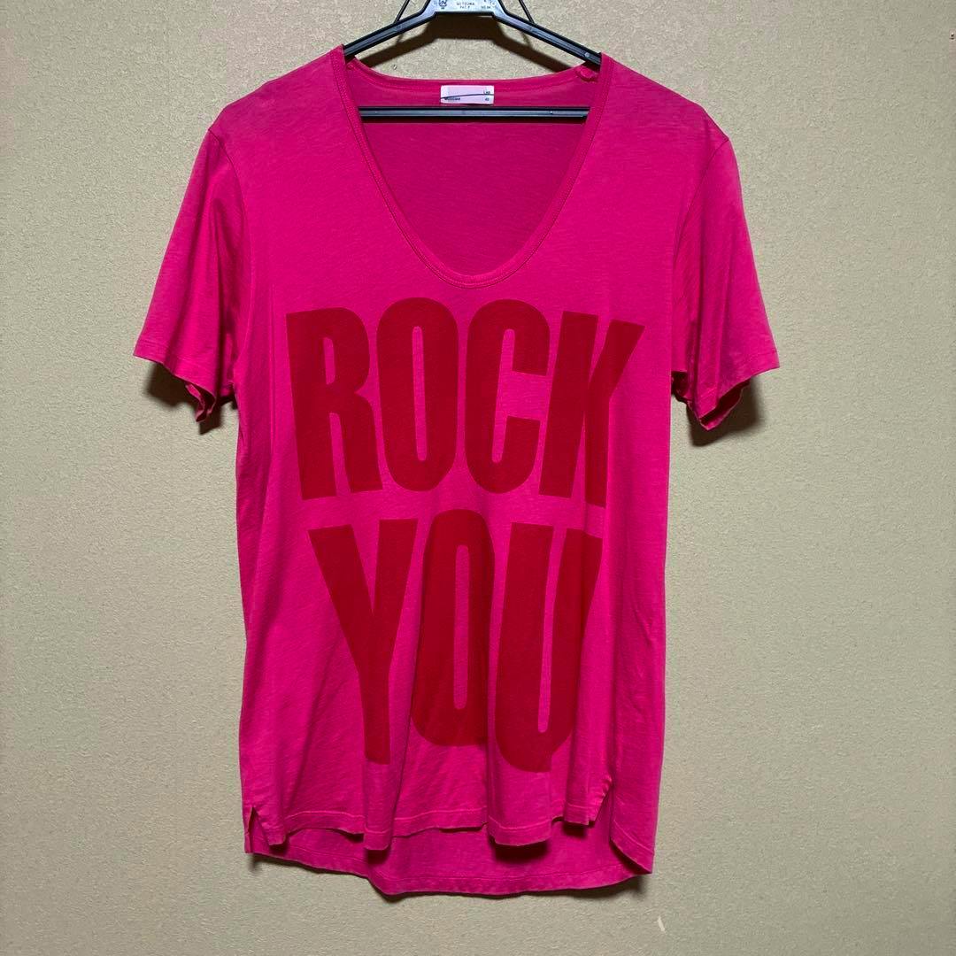 Pink LAD MUSICIAN T-shirt with large "ROCK YOU" front print hanging on a hanger against a wall.