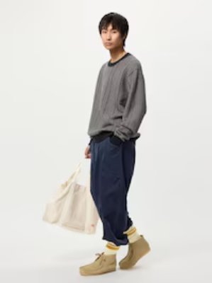 A full-body photo of a model wearing the crew-neck sweater and holding a large tote bag.