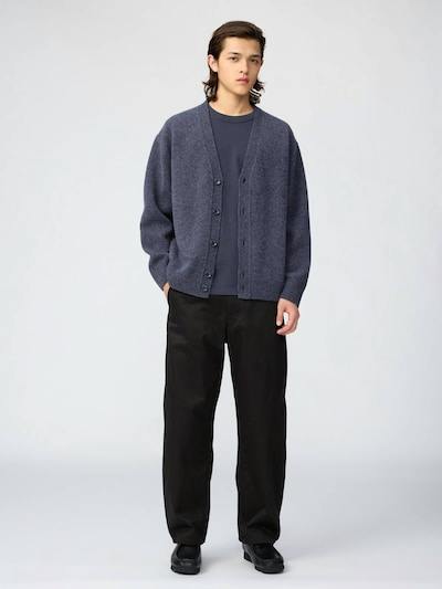 Male model wearing a blue V-neck wool cardigan, shown full-length over a t-shirt and trousers.