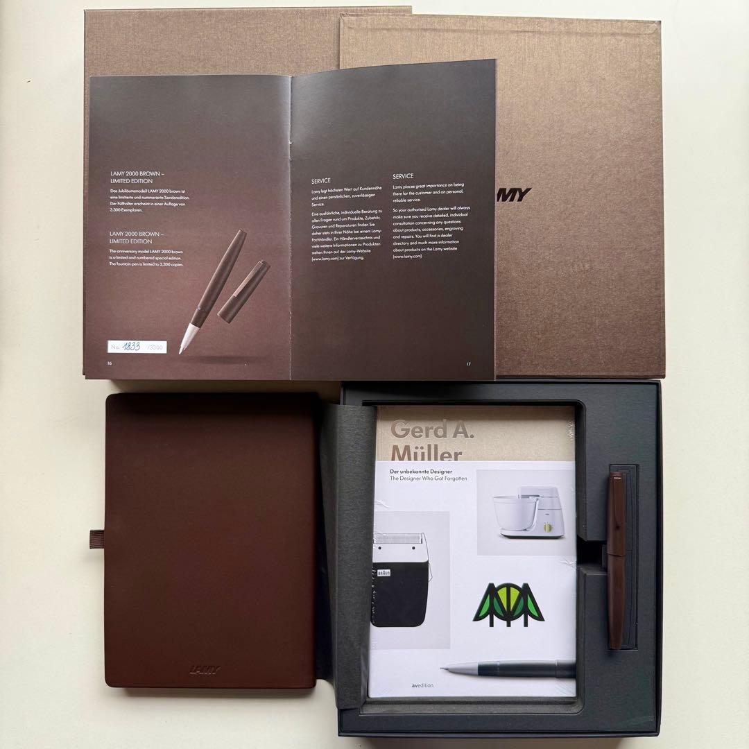 Open box showing the LAMY 2000 brown fountain pen in a foam tray alongside a notebook and paperwork.