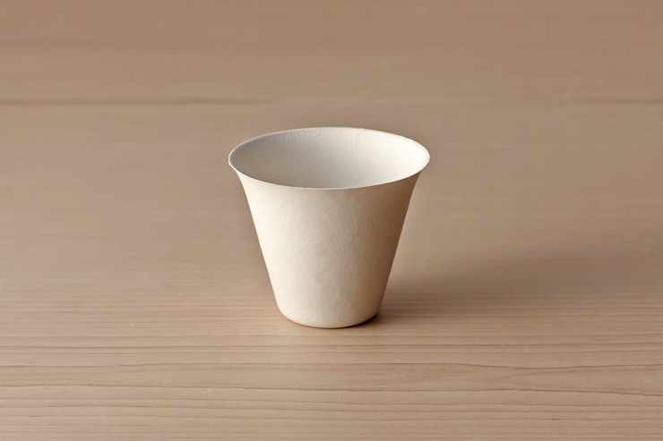 A single paper large tumbler cup shown from a slight side angle on a wooden surface.
