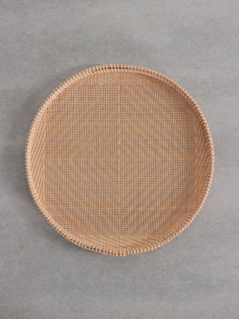 Top-down view of a round Vietnamese bamboo strainer on a gray background.