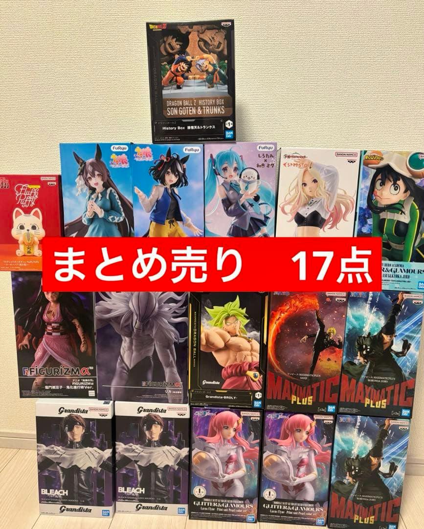 Photo of multiple boxed prize figures arranged in rows against a wall with a red banner across the center reading “まとめ売り 17点.”