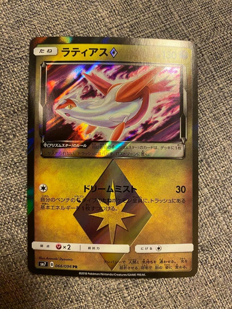 Front photo of the ラティアス♢ PR SM7 裂空のカリスマ 066/096 trading card showing its holographic artwork on a fabric background.