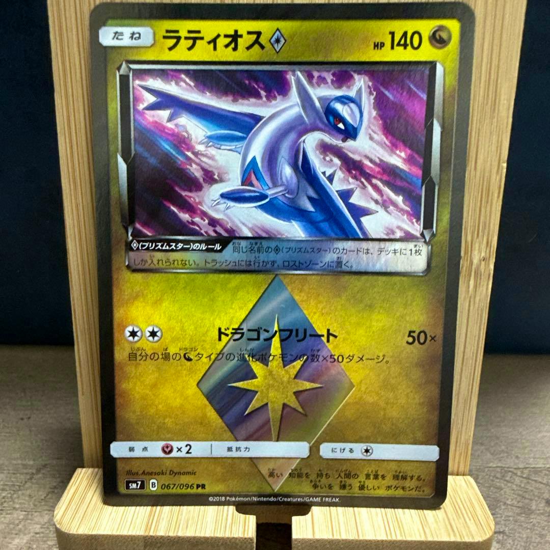 Front photo of the ラティオス (Latios) PR trading card (SM7 067/096) displayed upright on a wooden stand.