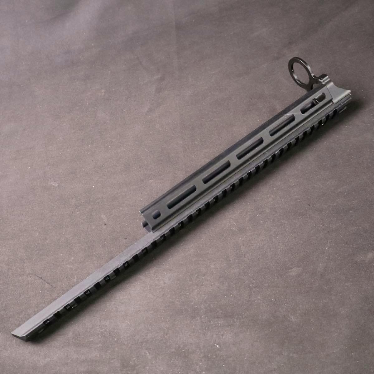 Black M-LOK top rail accessory for a Tokyo Marui M870 Breacher shown on a dark background.