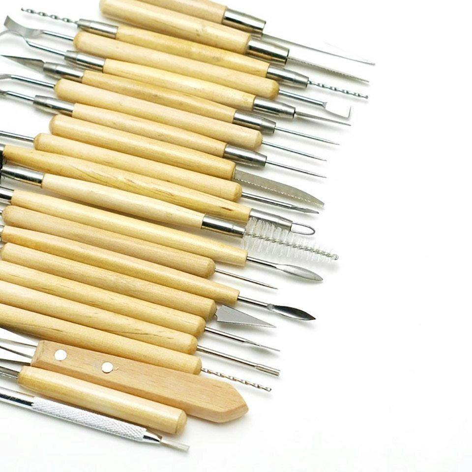A set of wood-handled clay sculpting chisels and pottery tools with various metal tips arranged on a white background.