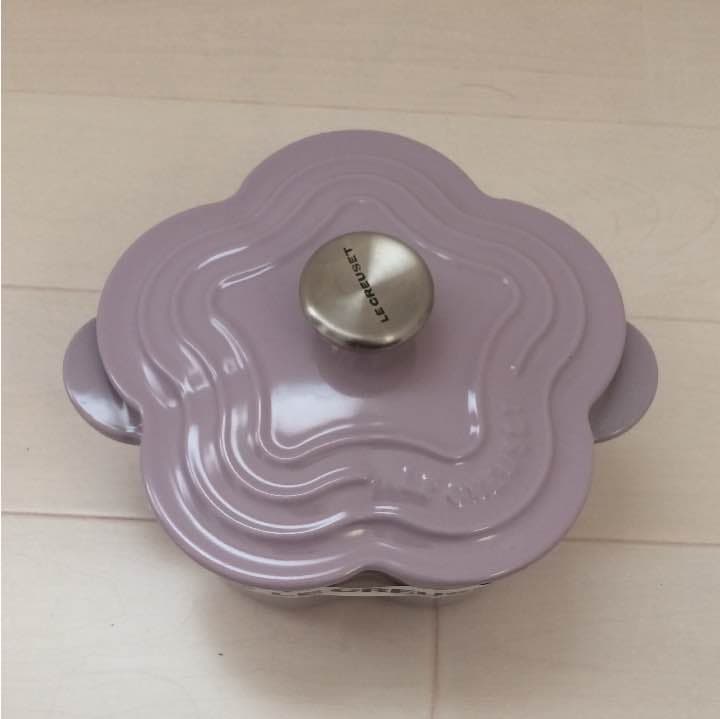 Top-down photo of a lavender Le Creuset Petit Fleur enameled cast iron pot showing the flower-shaped lid and metal knob.