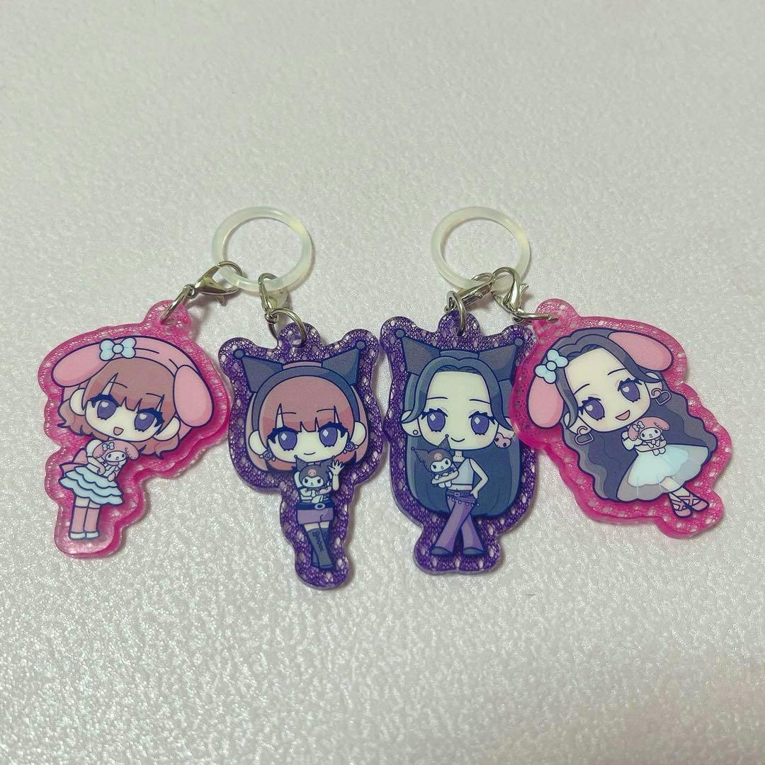Four acrylic LE SSERAFIM keychain charms featuring chibi character designs arranged side by side on a textured surface.