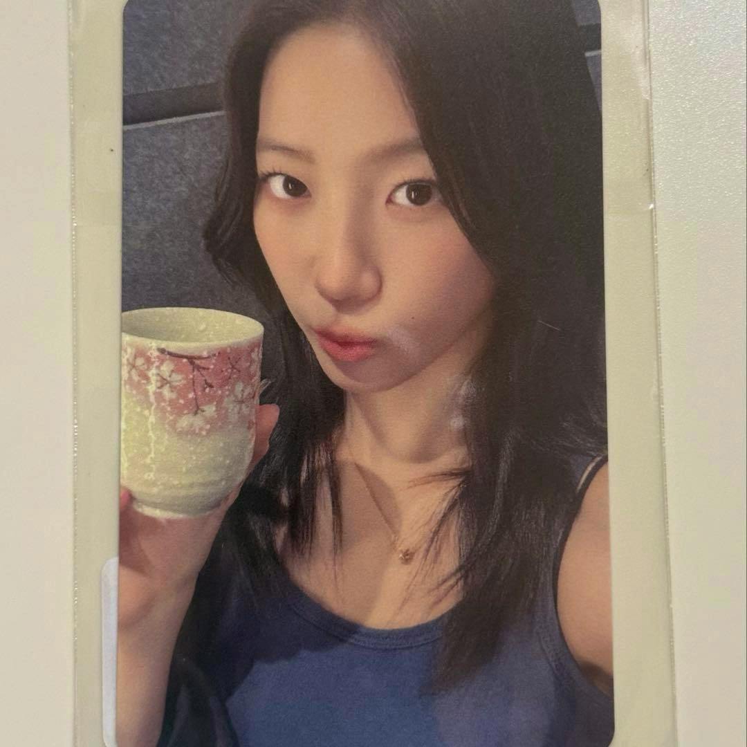 Photocard showing a young woman holding a patterned ceramic cup against a plain background.