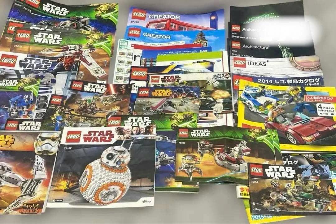 Many LEGO instruction manuals, catalogs, and posters, including Star Wars and Creator covers, spread out on a flat surface.