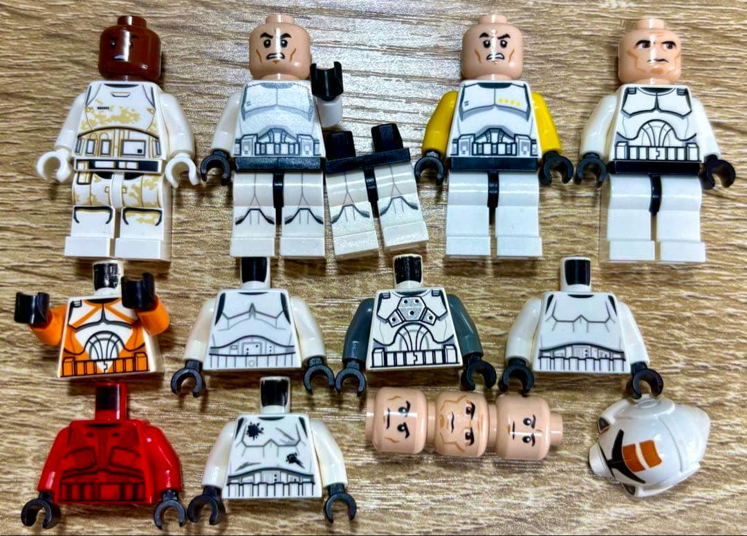 Multiple LEGO Star Wars trooper minifigure parts (torsos, legs, heads, and a helmet) laid out on a wood surface.